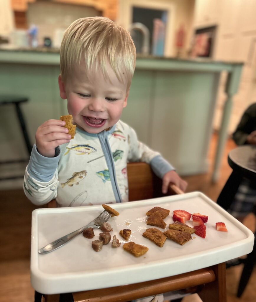 young child eating with "dine out tray" on wooden high chair